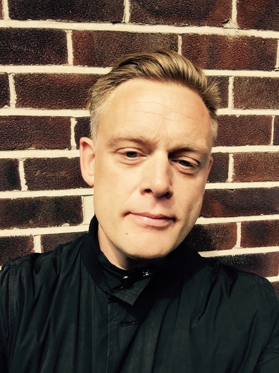 Portrait of Andrew Melchior against a brick wall.