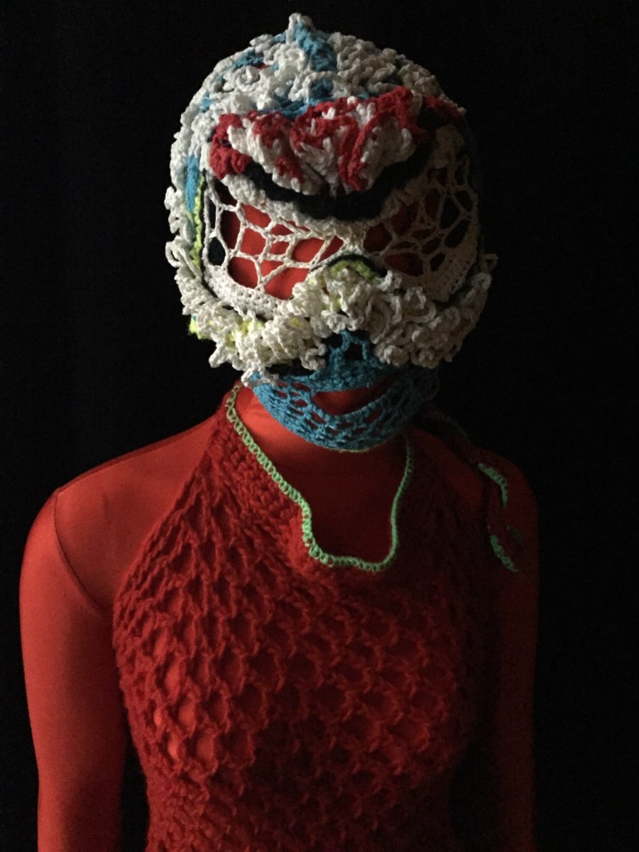 Björk wearing a red bodysuit and a crocheted mask.