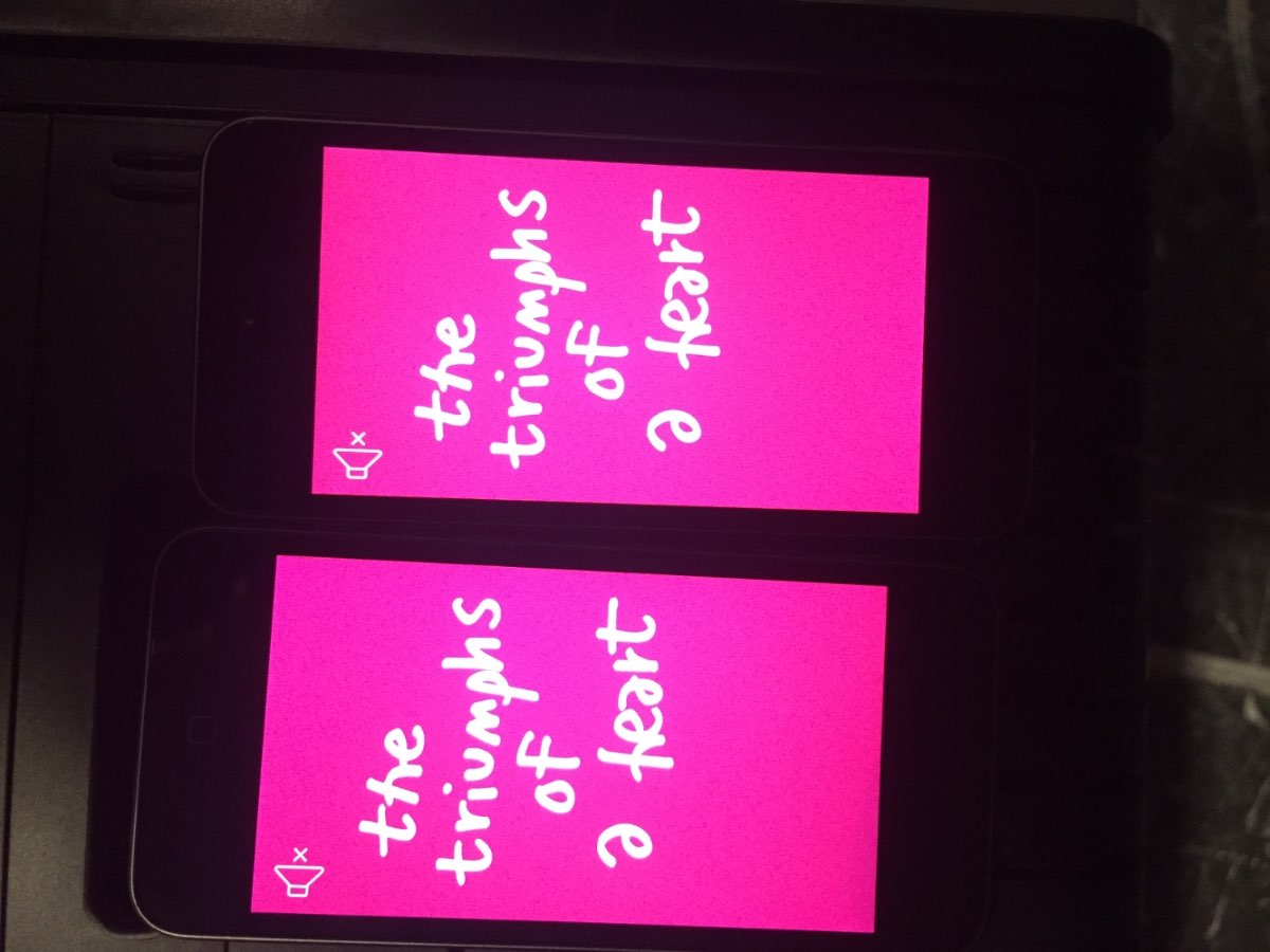 'The Triumph of a Heart' text projected in magenta in a darkened MoMA gallery.