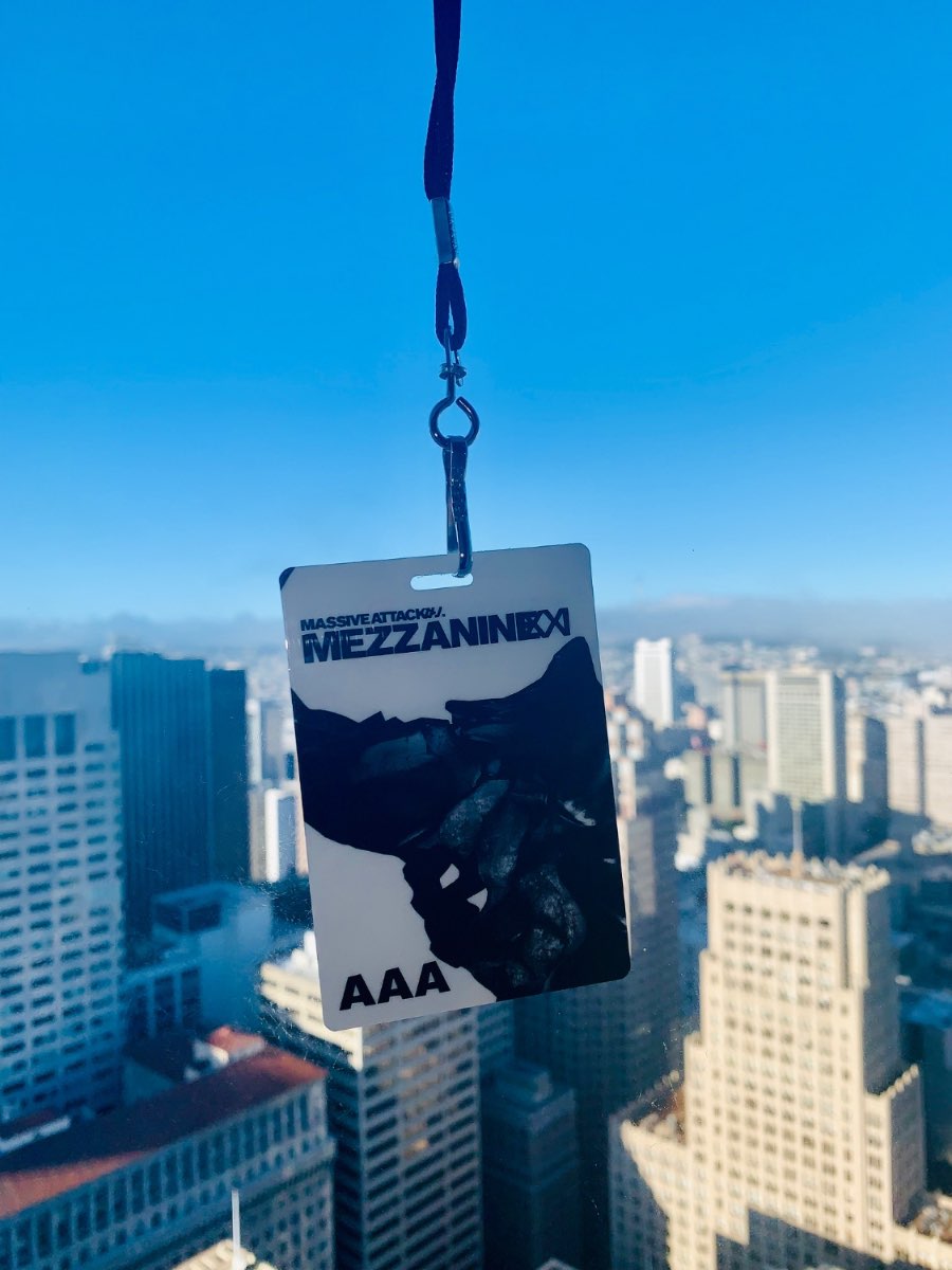A Mezzanine XXI AAA tour laminate held against a city skyline.