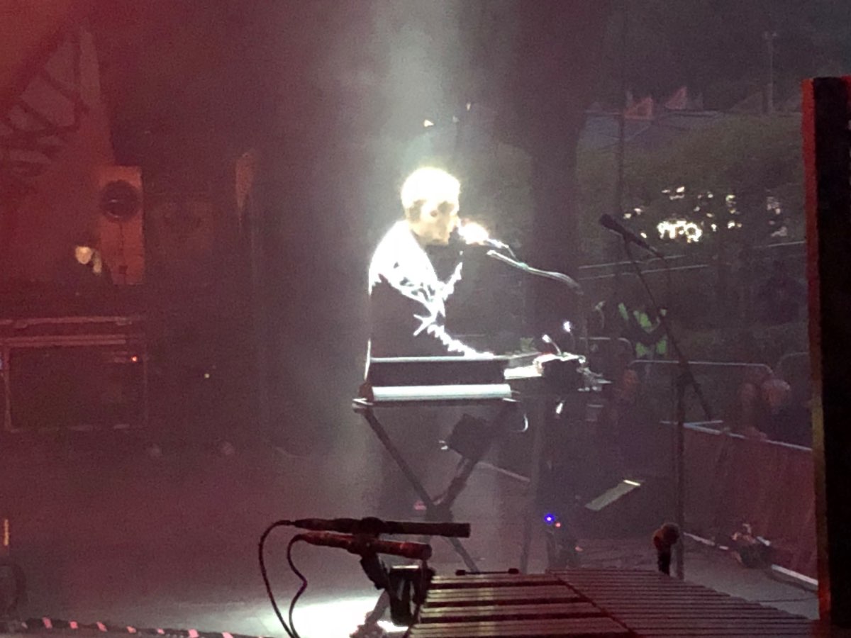 Massive Attack live — a performer at a keyboard under a shaft of spotlight.