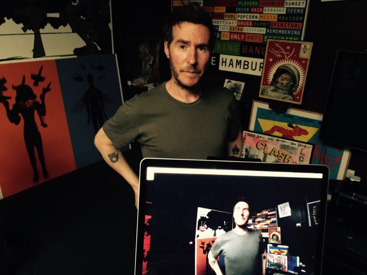 Andrew Melchior in the studio surrounded by screens and artwork.