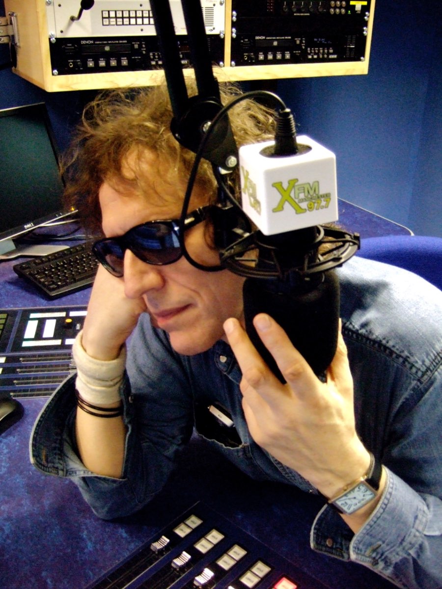 Mick Rock at the XFM radio microphone wearing sunglasses.