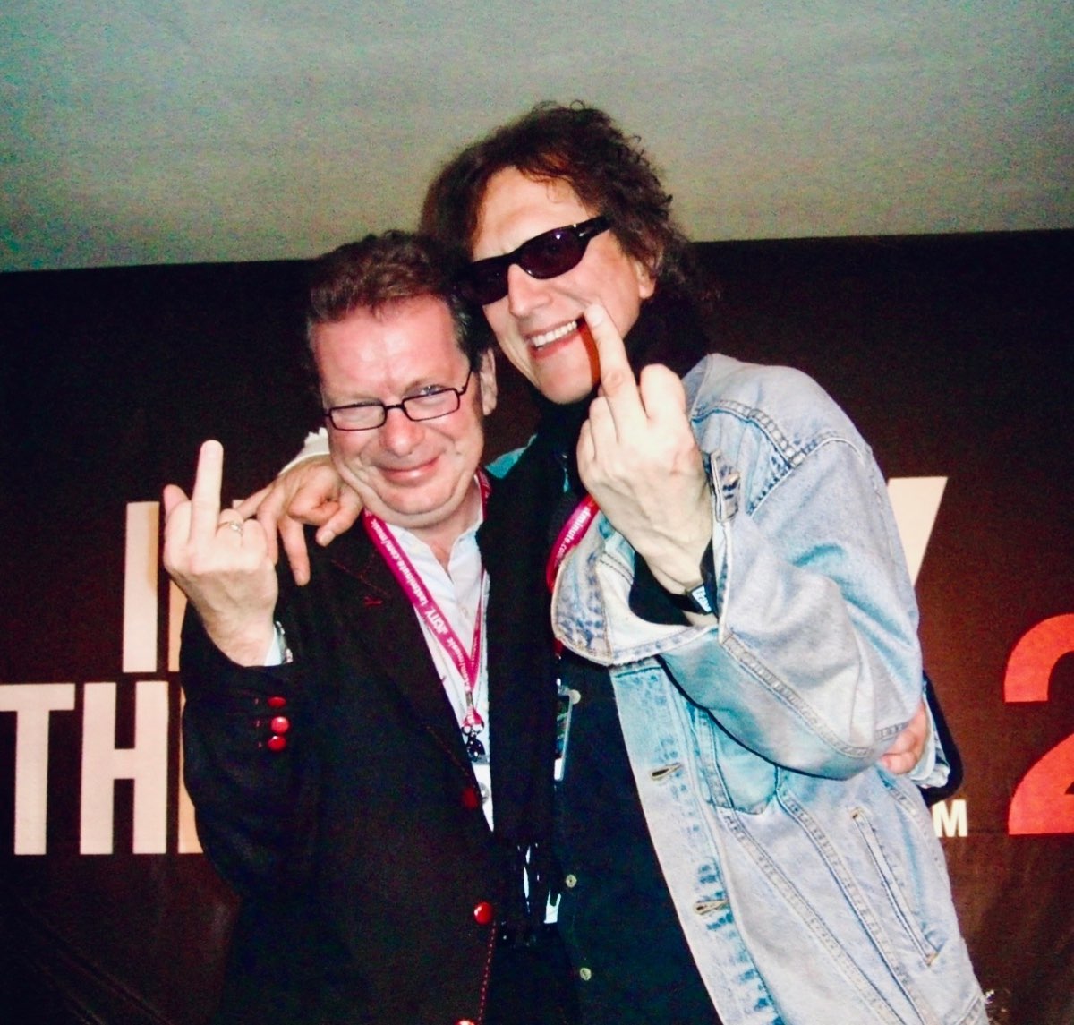 Andrew Melchior and Mick Rock at a film event, both mugging for the camera.