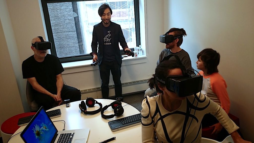 Andrew Melchior with collaborators testing early virtual-reality headsets around a studio table.